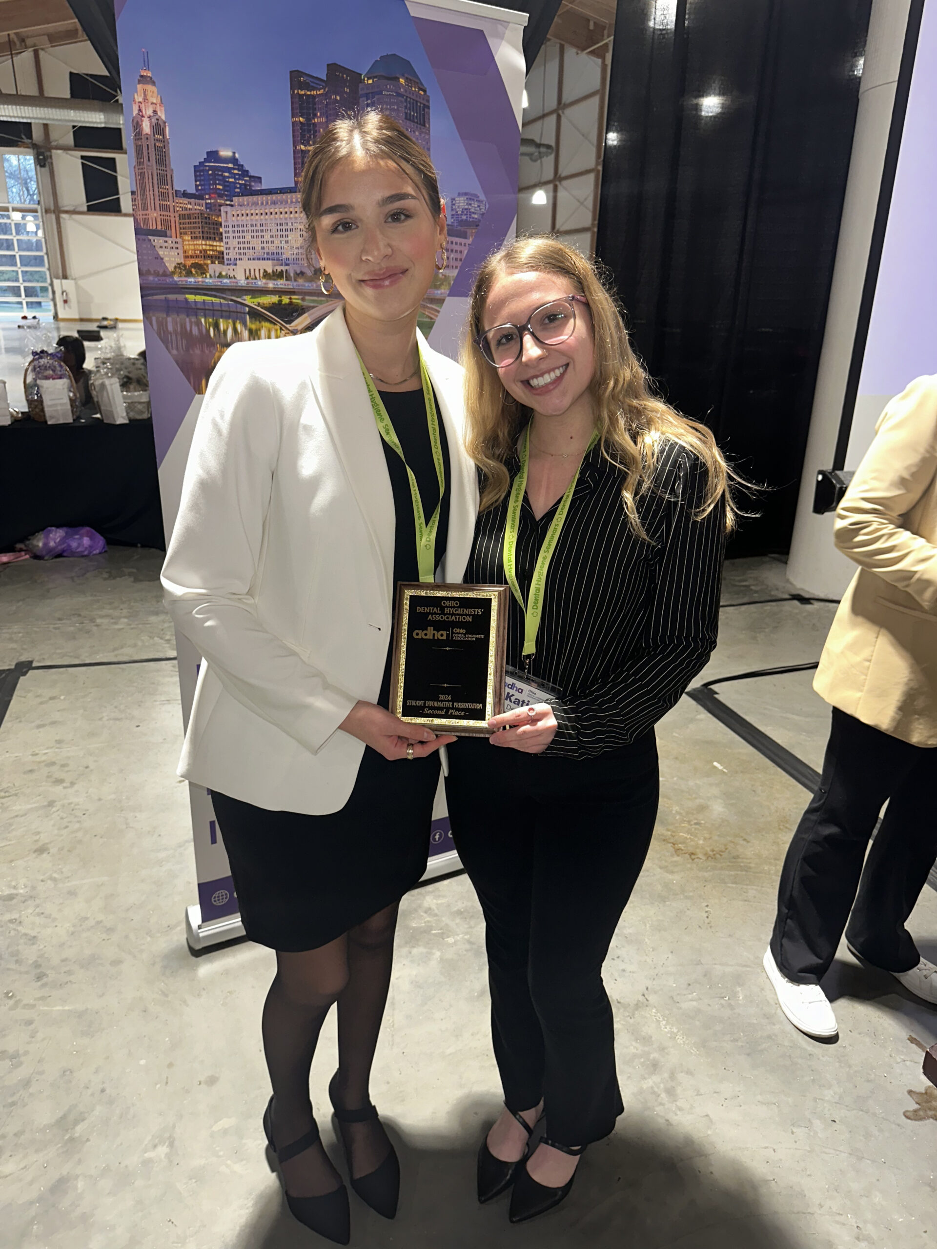 Two women holding a plaque and smiling for the camera.