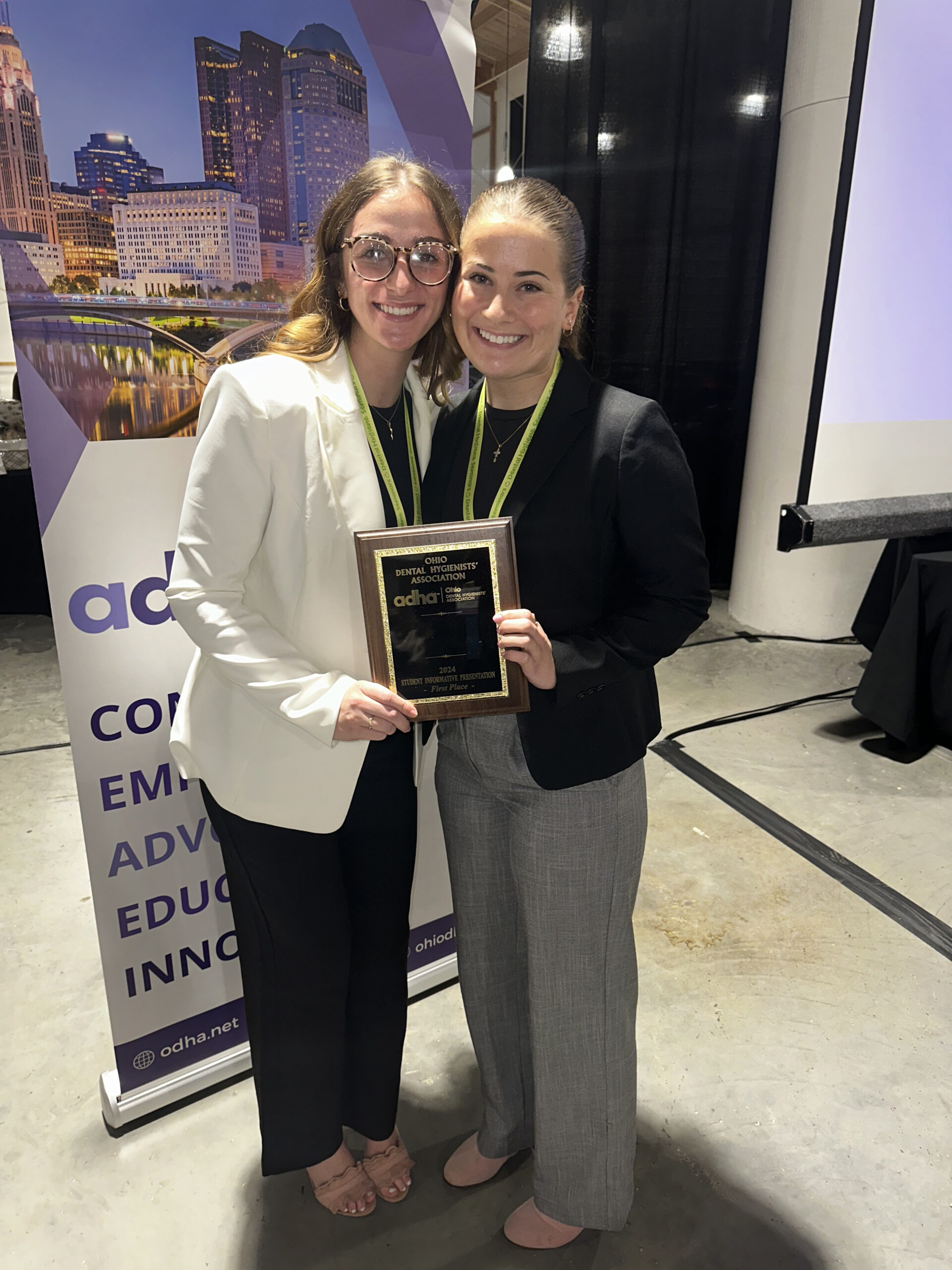 Two women holding a plaque and smiling for the camera.